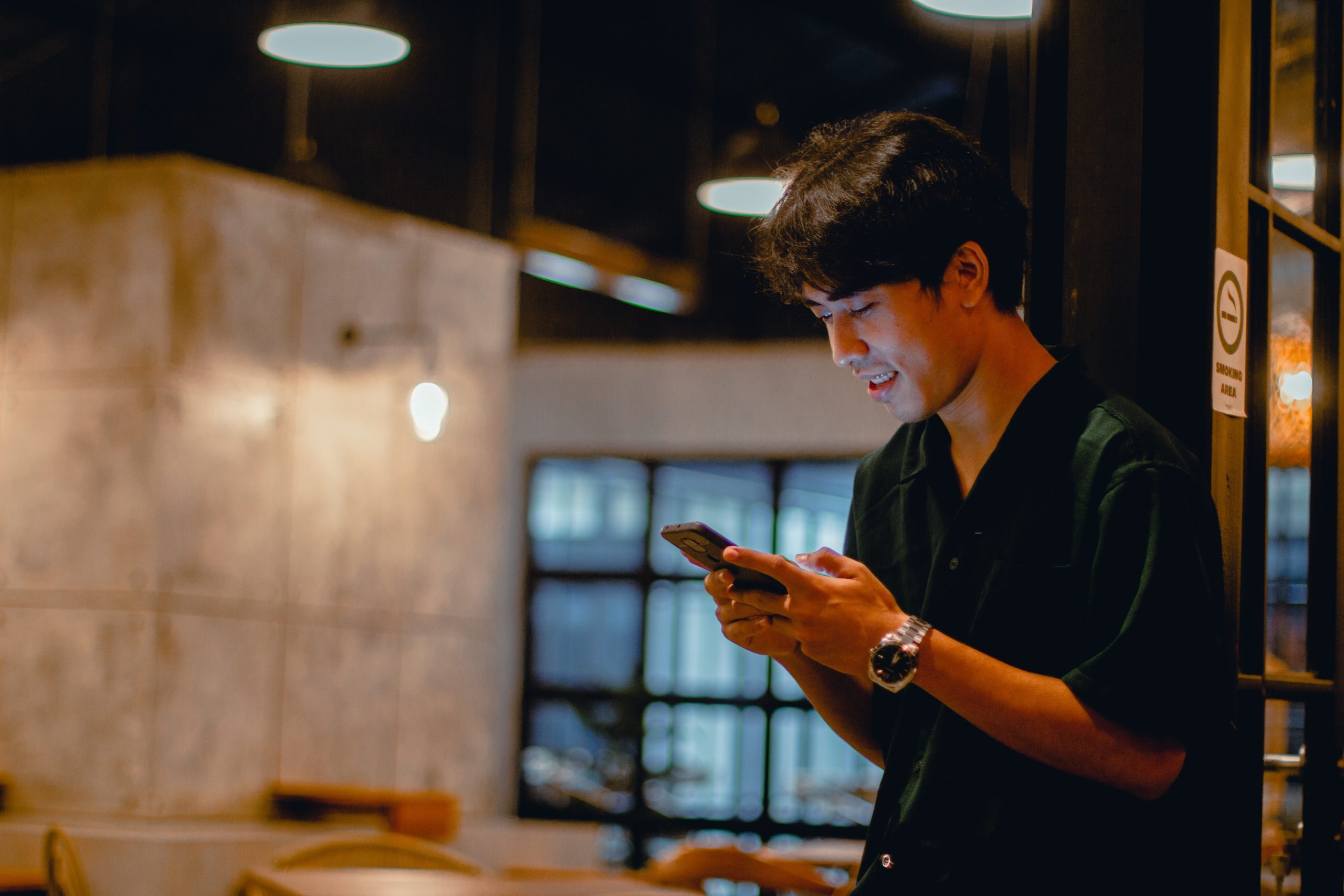 Young, Asian man using his mobile device in a restaurant.